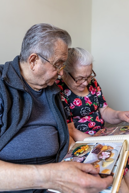 Foto gratuita una pareja de ancianos está mirando fotografías en un álbum de fotos familiar.