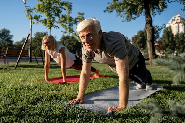 Pareja de ancianos practicando yoga al aire libre