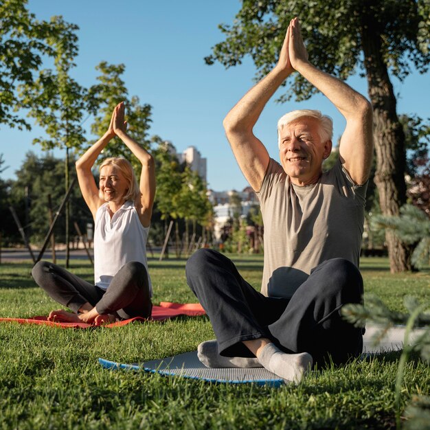 Pareja de ancianos practicando yoga al aire libre