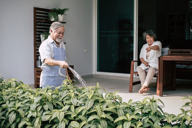 Pareja de ancianos regando una flor en casa jardín