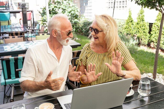Pareja de ancianos riéndose juntos delante de una computadora portátil