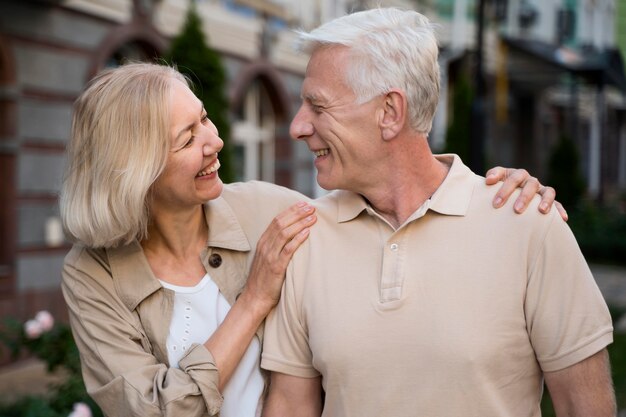 Pareja de ancianos sonriente dando un paseo por la ciudad juntos