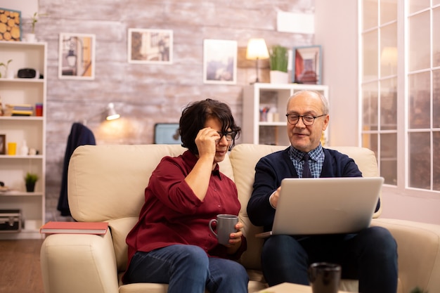 Pareja de ancianos usando una computadora portátil moderna para charlar con su nieto. Abuela y abuelo con tecnología moderna.