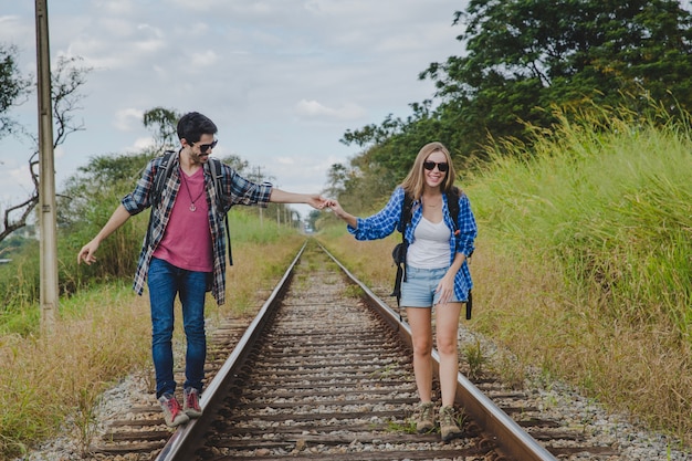 Pareja andando en vías de tren y tomándose las manos