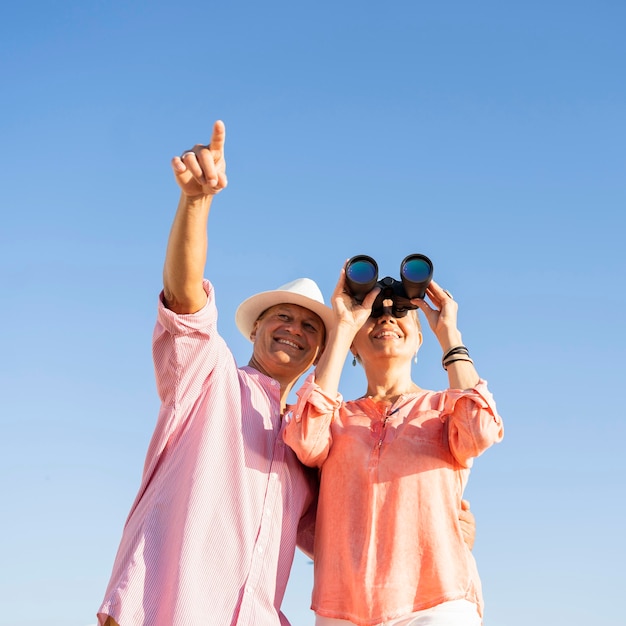 Foto gratuita pareja de ángulo bajo con binoculares