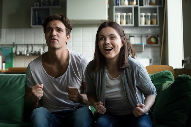 Pareja animando apoyando al equipo ganador viendo el juego de televisión en casa