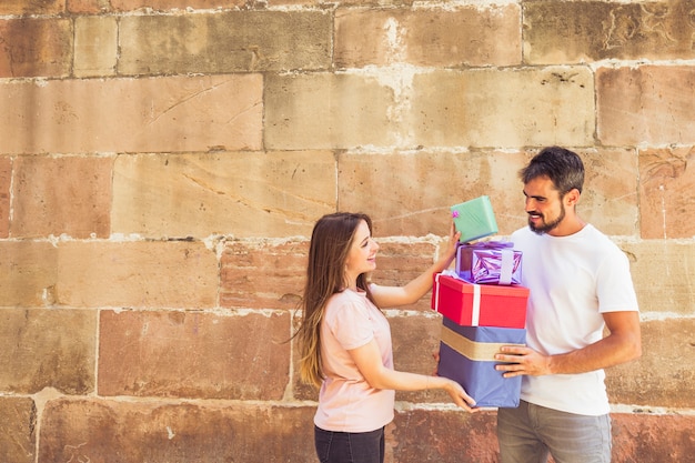 Pareja apilando regalos frente a la pared