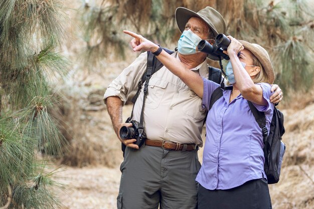 Pareja apreciando la belleza de la naturaleza con binoculares durante la nueva normalidad