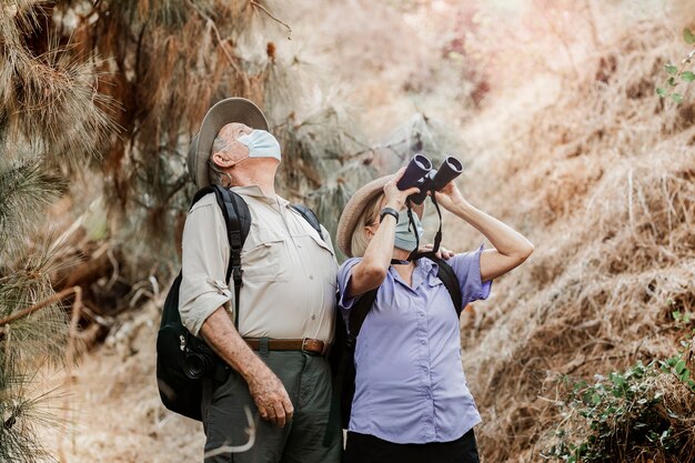 Pareja apreciando la belleza de la naturaleza con binoculares durante la nueva normalidad