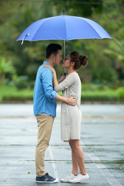 Pareja asiática besándose bajo la lluvia