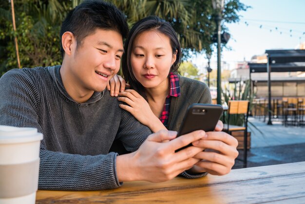 Pareja asiática mirando el teléfono móvil.