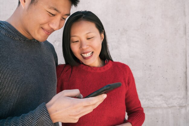 Pareja asiática mirando el teléfono móvil.