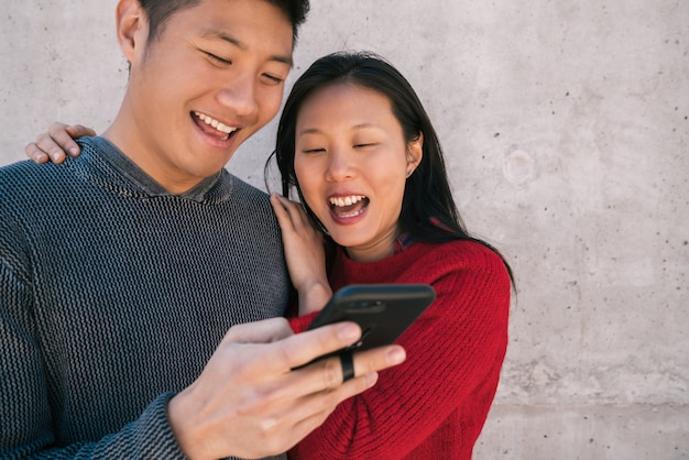 Pareja asiática mirando el teléfono móvil.