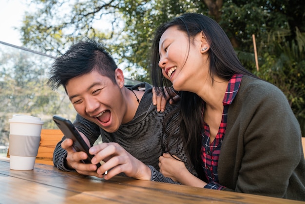 Pareja asiática mirando el teléfono móvil.