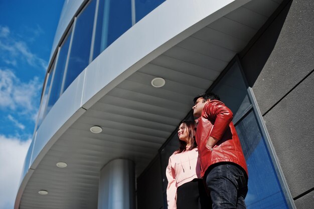 Pareja asiática de pie juntos contra un nuevo edificio moderno y mira el cielo