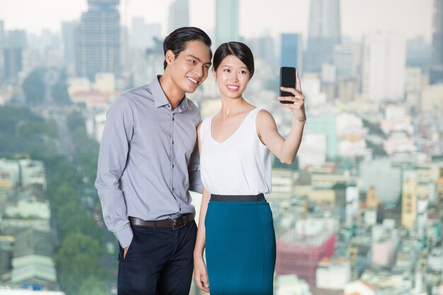 Pareja asiática que toma la foto con el teléfono inteligente selfie
