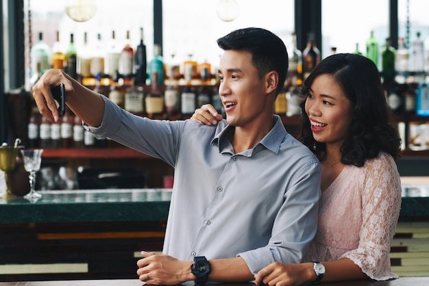 Pareja asiática tomando selfie en smartphone en bar