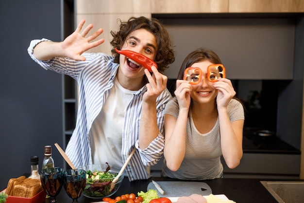 Pareja atractiva alegre con pimiento rojo debajo de los ojos