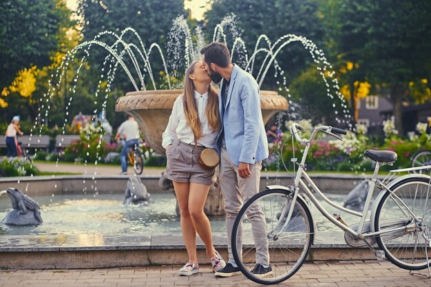 Una pareja atractiva en una cita se besa sobre el fondo de la fuente.