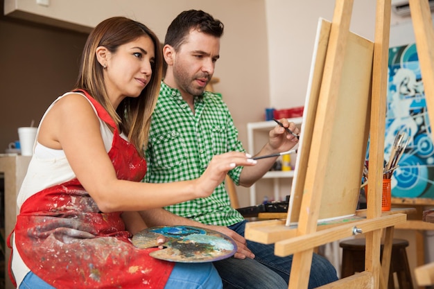 Foto gratuita pareja atractiva de jóvenes artistas trabajando juntos en un proyecto en un taller