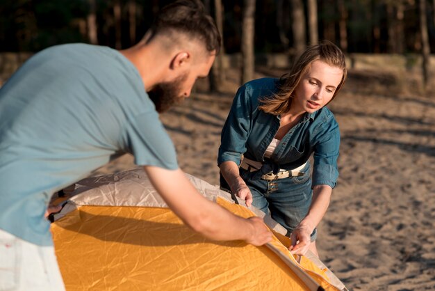 Pareja ayudándose mutuamente a poner la carpa