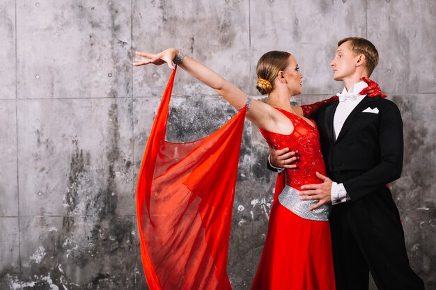 Pareja bailando baile apasionado junto a la pared gris