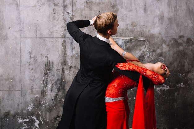 Pareja bailando cerca de la pared gris