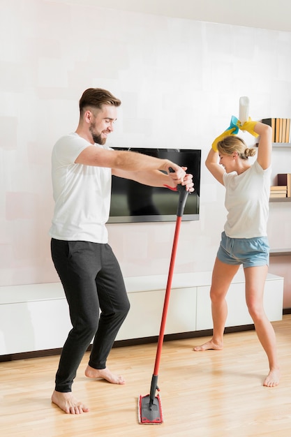 Pareja bailando en interiores con accesorios de limpieza