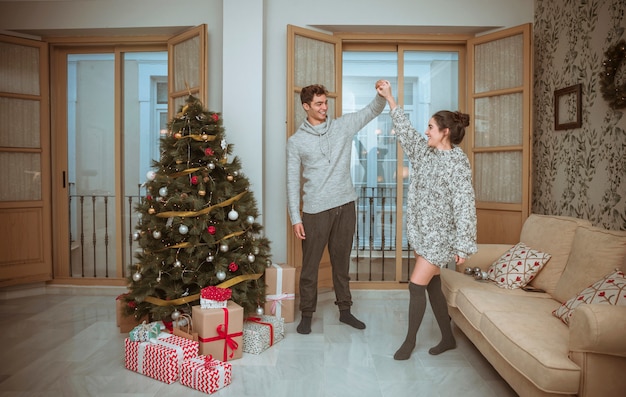 Pareja bailando en la sala decorada para navidad