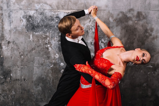 Pareja bailando sensual baile cerca de la pared gris