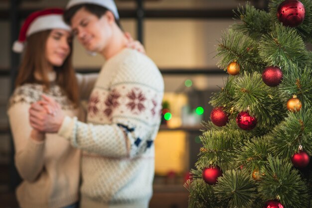 Pareja bailando vals junto al árbol de navidad