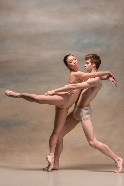 Pareja de bailarines de ballet posando sobre espacio gris