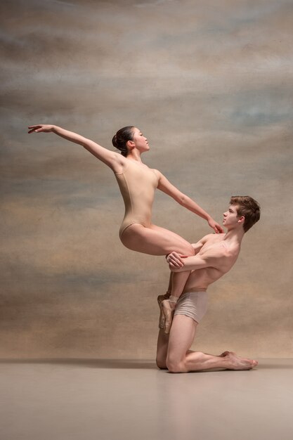 Pareja de bailarines de ballet posando sobre espacio gris