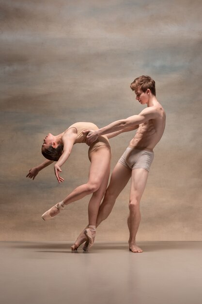 Pareja de bailarines de ballet posando sobre espacio gris