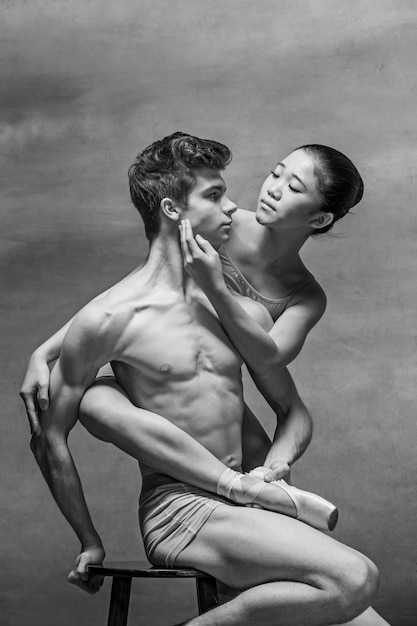 Pareja de bailarines de ballet posando sobre gris