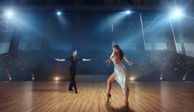 Pareja de bailarines realizan bailes latinos en un gran escenario profesional