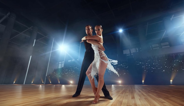 Foto gratuita pareja de bailarines realizan bailes latinos en un gran escenario profesional