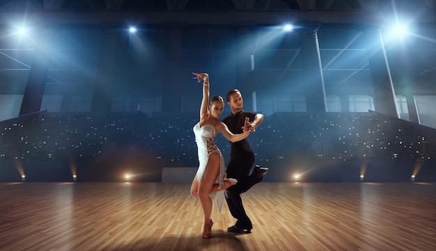 Pareja de bailarines realizan bailes latinos en un gran escenario profesional