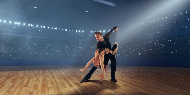 Pareja de bailarines realizan bailes latinos en un gran escenario profesional