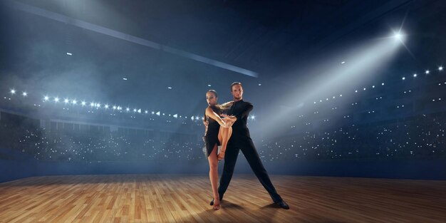 Pareja de bailarines realizan bailes latinos en un gran escenario profesional