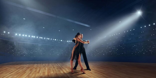 Pareja de bailarines realizan bailes latinos en un gran escenario profesional