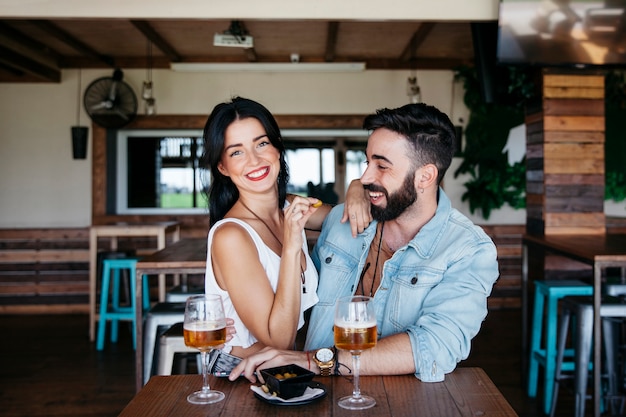 Pareja en bar riendo con cerveza