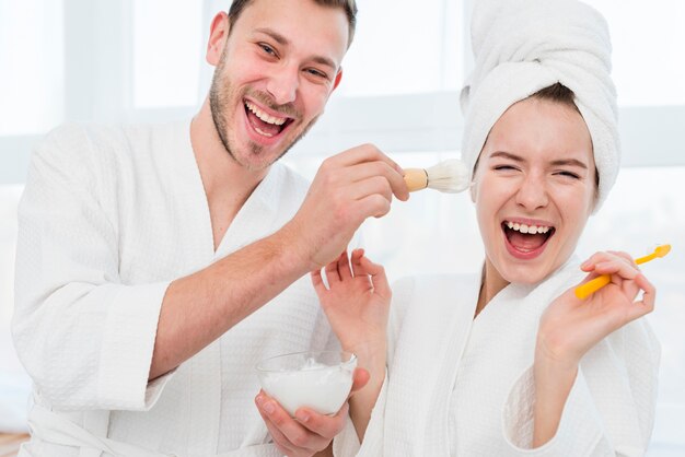 Pareja en batas de baño jugando con espuma de afeitar