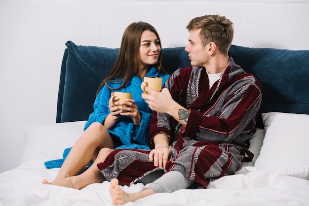 Pareja en batas de baño tomando café en la cama