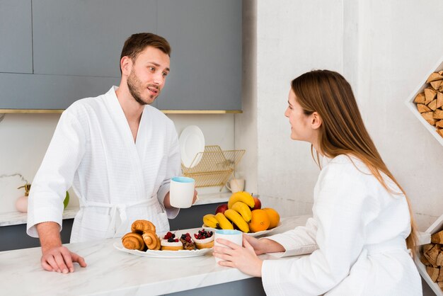 Pareja en batas de baño tomando un café en la cocina