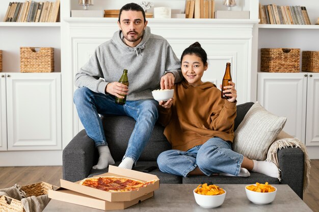 Pareja bebiendo cerveza y comiendo bocadillos en el interior