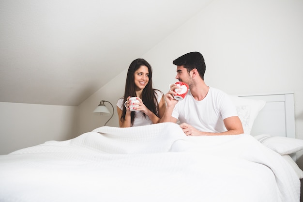 Pareja bebiendo de unas tazas de café en la cama