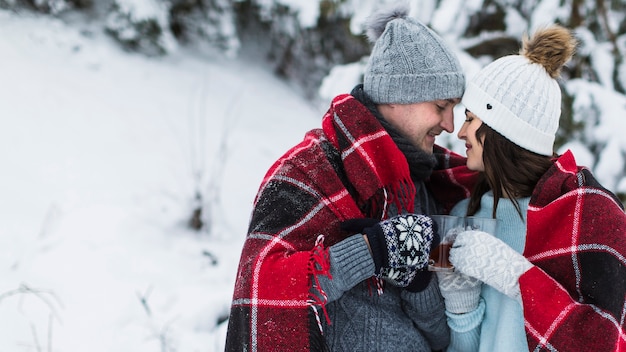 Foto gratuita pareja bebiendo té en el bosque de invierno