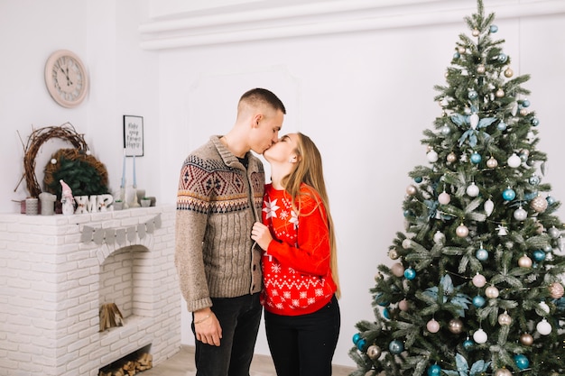 Pareja besándose y celebrando navidad en casa