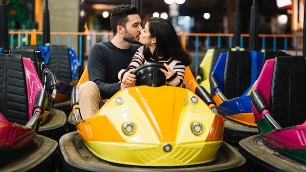 Pareja besándose en los coches de choque